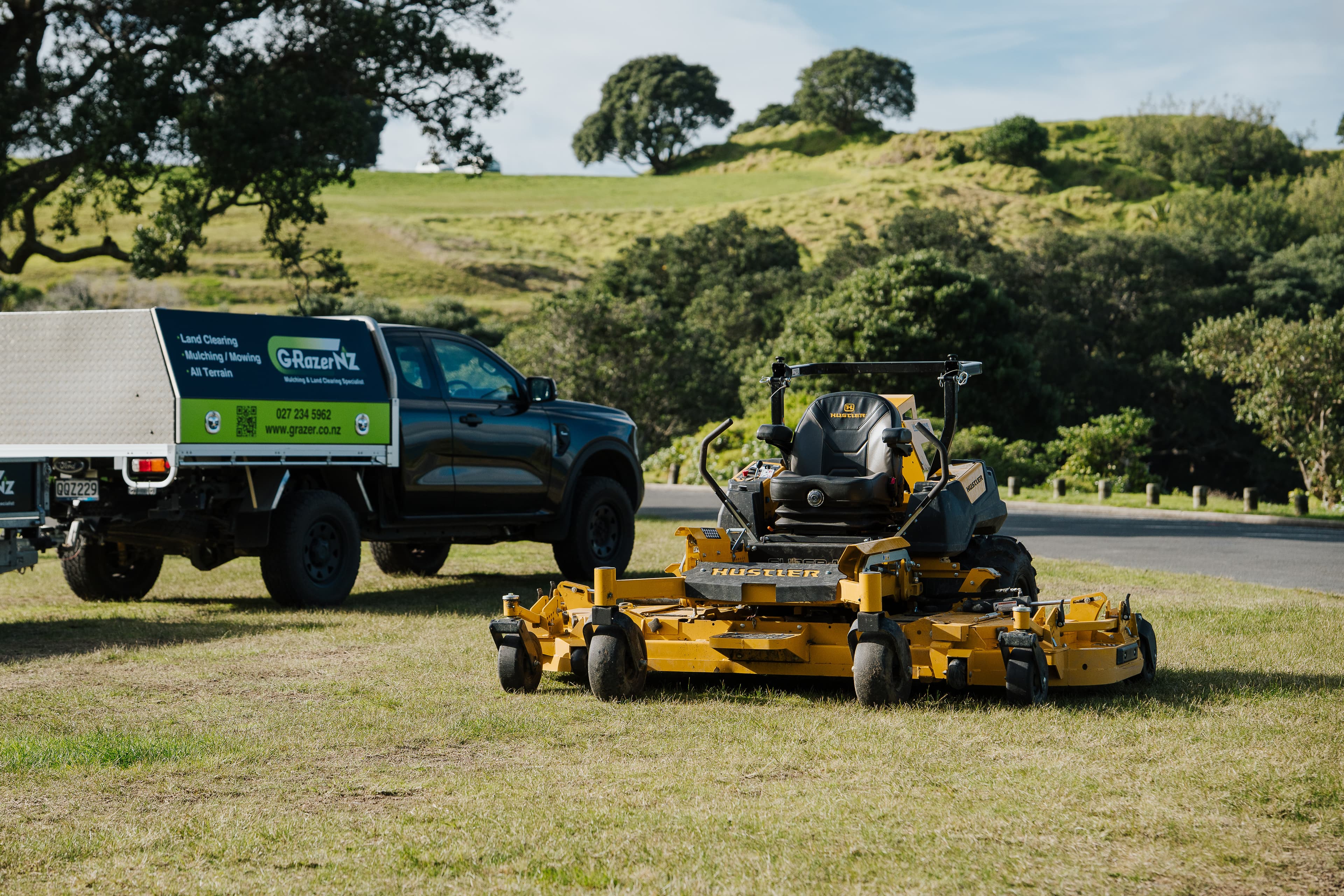 Bea the Hustler ride-on mower beside the GRazer NZ truck and trailer